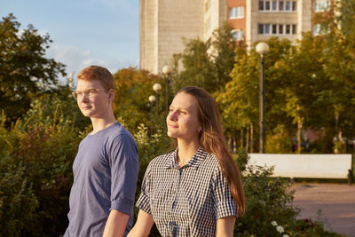 Portrait of young couple standing against trees
