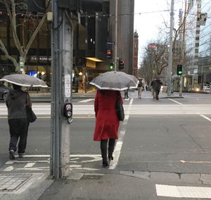 Rear view of people walking on street in city