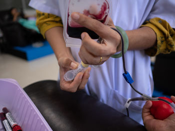 Close-up of doctor holding bag while standing by patient during donation 