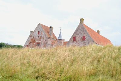 Old house on field against sky