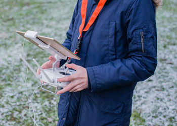 Midsection of man holding drone remote on field