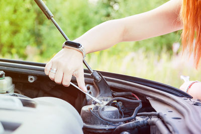 Cropped hand of woman repairing engine of car