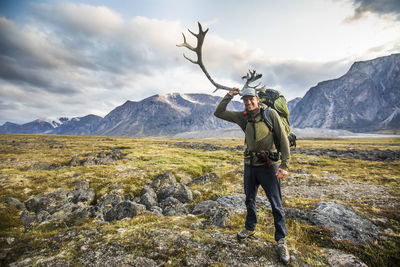 Backpacker holds caribou antler in auyuittuq national park, canada.