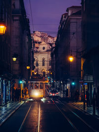 Illuminated street amidst buildings at night