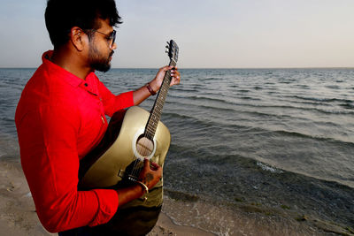 Man playing guitar on beach