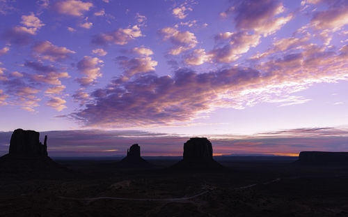 Silhouette rock formations on landscape against sky during sunset