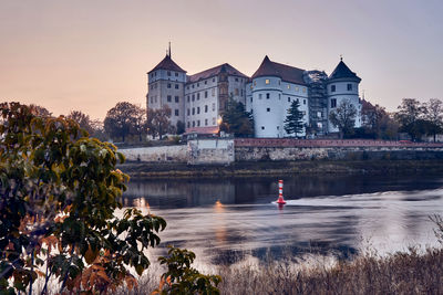 View of buildings by river against sky in city