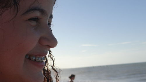 Close-up of smiling young woman with braces against sky at beach