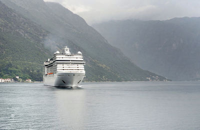 Boat sailing on sea by mountain against sky