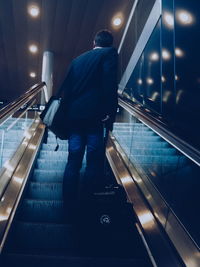 Full length of businessman with luggage in escalator at airport