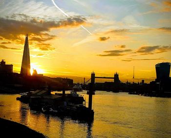 Silhouette sailboats in river against sky during sunset