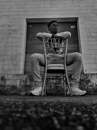 Man sitting on chair against wall