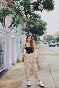 Portrait of young woman standing on footpath