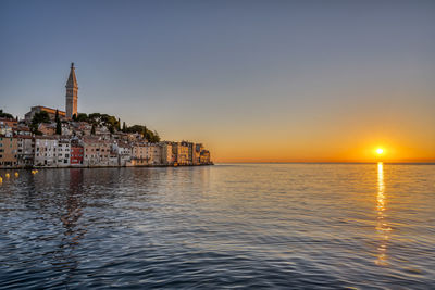 Scenic view of sea against buildings during sunset