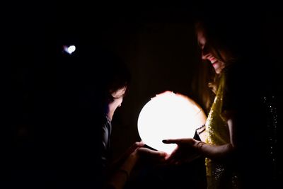 People holding lit candle in the dark