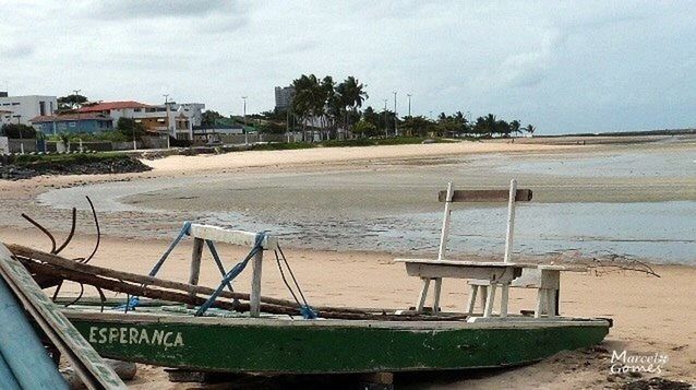 water, sea, beach, sky, nautical vessel, moored, boat, shore, transportation, built structure, sand, mode of transport, cloud - sky, architecture, building exterior, nature, day, horizon over water, cloudy, incidental people