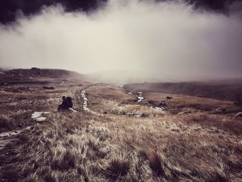 Scenic view of field against cloudy sky