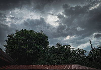 Low angle view of trees and building against sky