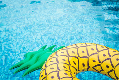 High angle view of pineapple inflatable ring floating on swimming pool