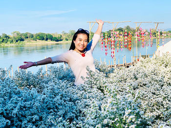 Happy young woman with arms raised on flower