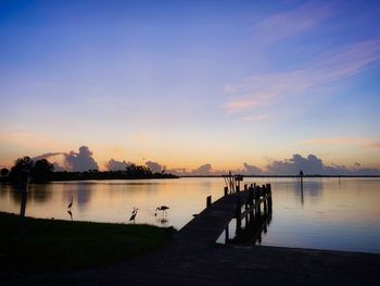 Pier on lake against sky during sunset