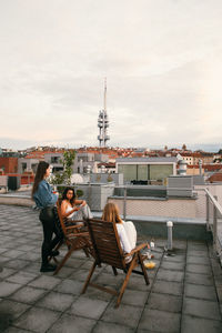 People sitting on seat against buildings in city