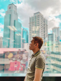 Side view of man looking at city buildings