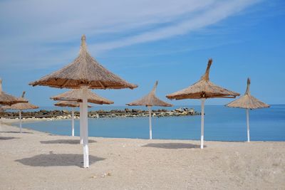 Traditional windmill on beach against sky