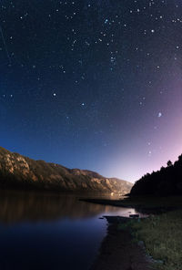 Scenic view of lake and mountains against sky at night