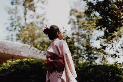 Rear view of woman standing against trees
