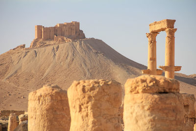 Old architectural columns in desert against mountain