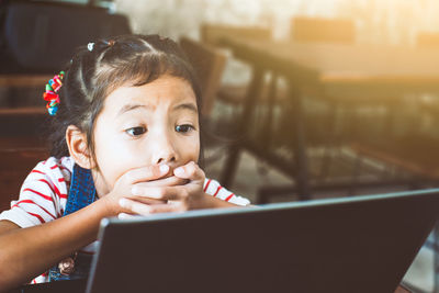 Shocked schoolgirl looking at laptop in classroom