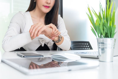 Midsection of woman using mobile phone while sitting on table