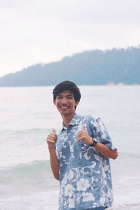 Portrait of smiling young man standing on sea shore