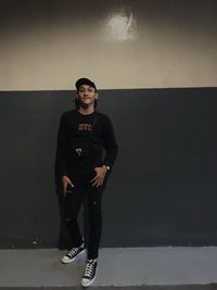 Portrait of young man standing against wall