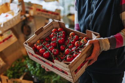 Shop assistant holding crate with tomatoes