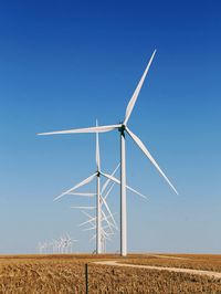 Wind turbines on field against blue sky