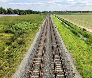 Railroad tracks on field against sky