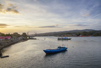 Boats moored in sea against sky during sunset, kendari city