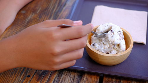 Close-up of hand holding ice cream on table