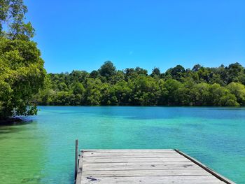 Scenic view of swimming pool by lake against clear blue sky