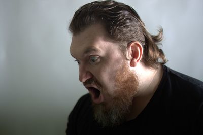 Close-up of man shouting against white wall