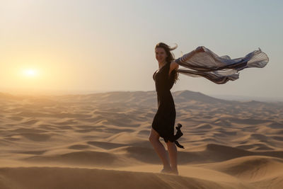 Portrait of woman standing on sand dune in desert
