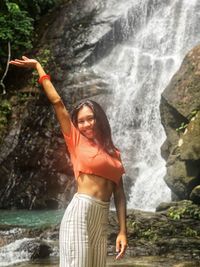 Woman standing on rock against waterfall