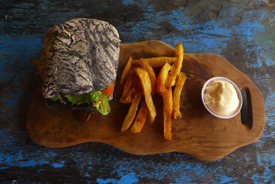 French fries served with cheese dip and rustic bread sandwich on cutting board
