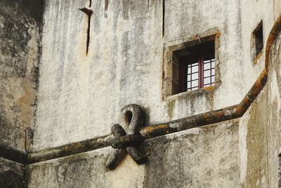 Low angle view of rusty window on wall