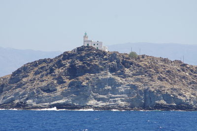 Lighthouse by sea against clear sky