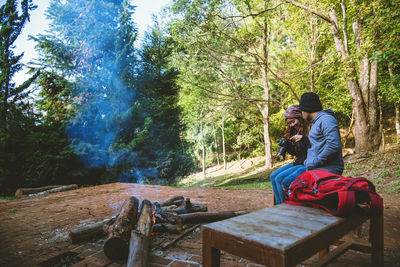 Rear view of friends sitting on wood in forest