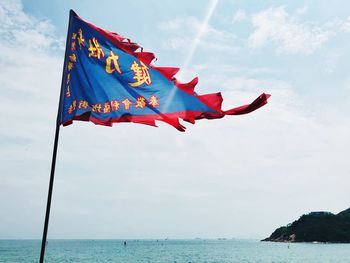 Low angle view of flags over sea against sky