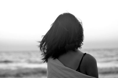 Rear view of woman at beach against sky